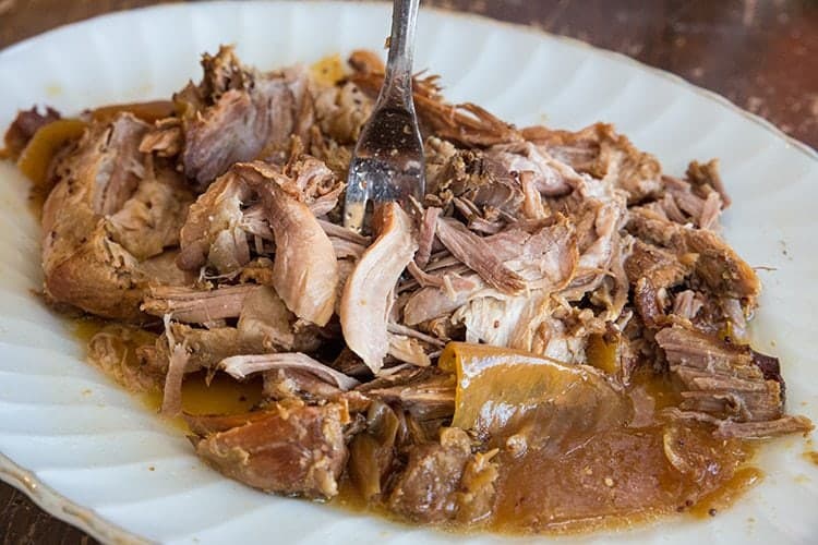 white plate with Crockpot Pulled Pork served with a little bit of the sauce