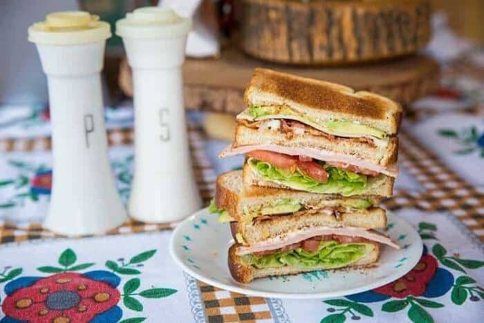 Stack of Ultimate Clubhouse Sandwiches in a White Plate, Salt and Pepper Shakers at the back