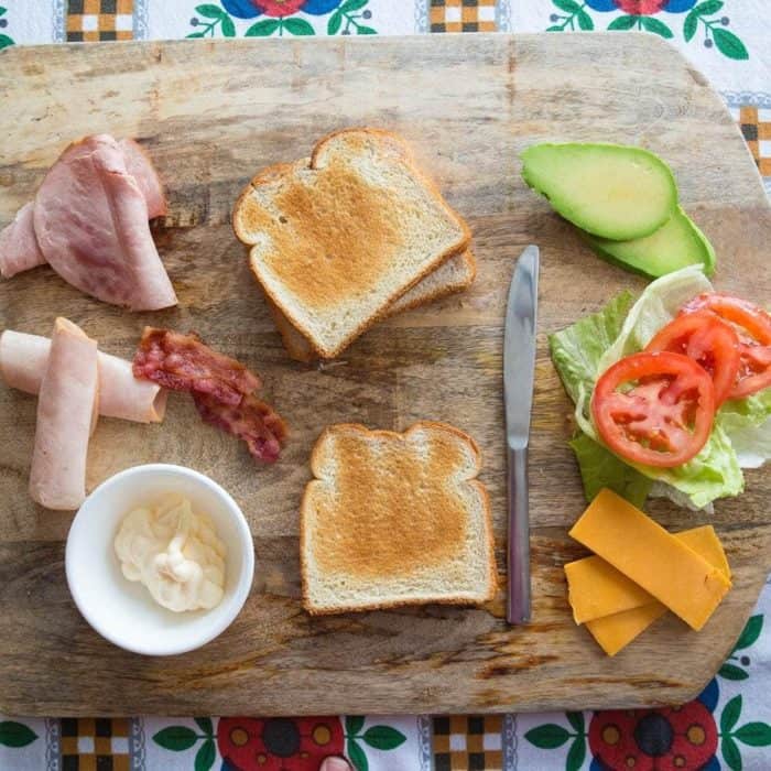 All ingredients needed in making the Clubhouse Sandwich on wooden board