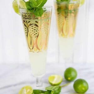 close up of Key Lime Mojito in pilsners with gold prints garnish with fresh mint and lime