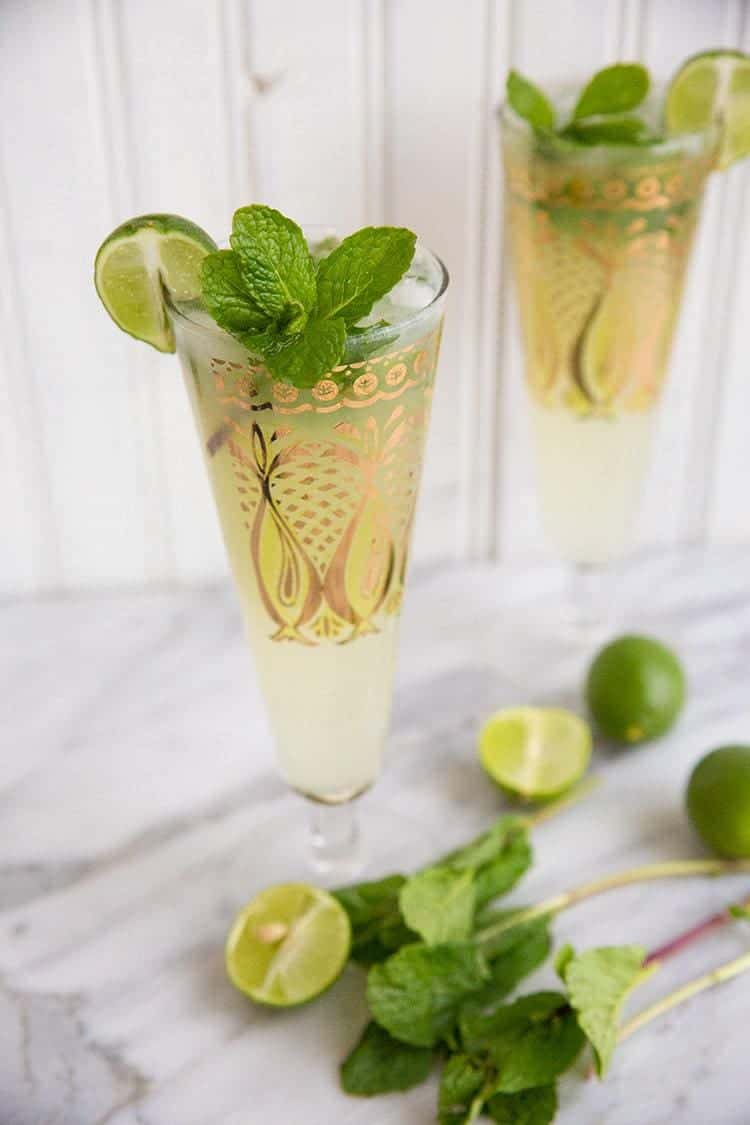 Key Lime Mojito in pilsners with gold prints garnish with fresh mint and lime on white background