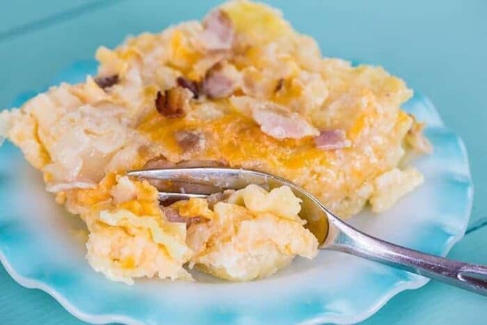 A serving of Lazy Perogy Casserole in ruffle plate on jade blue background