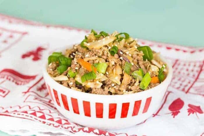 Crack Slaw in a white bowl with sprinkles of toasted sesame seeds and green onions