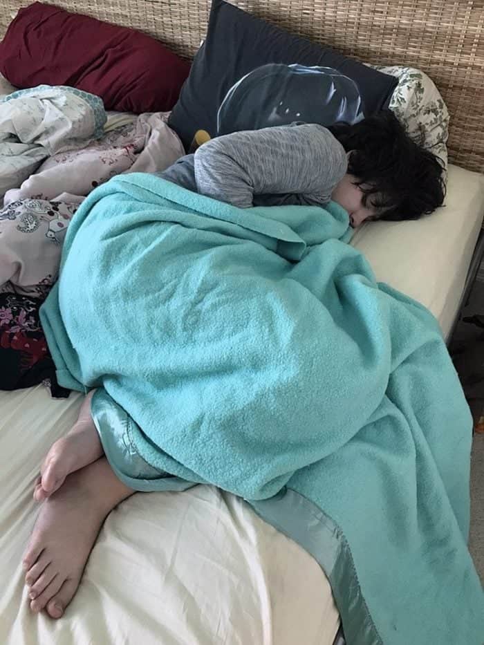 a kid sleeping in bed with fleece blanket