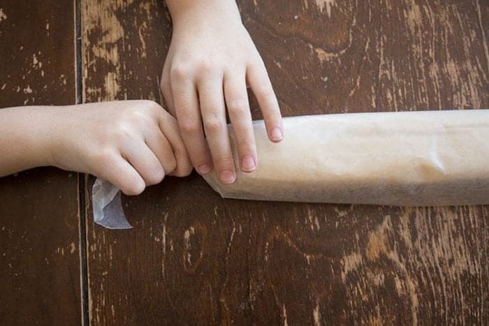 rolling up the combined ingredients of sugar cookies on a waxed paper