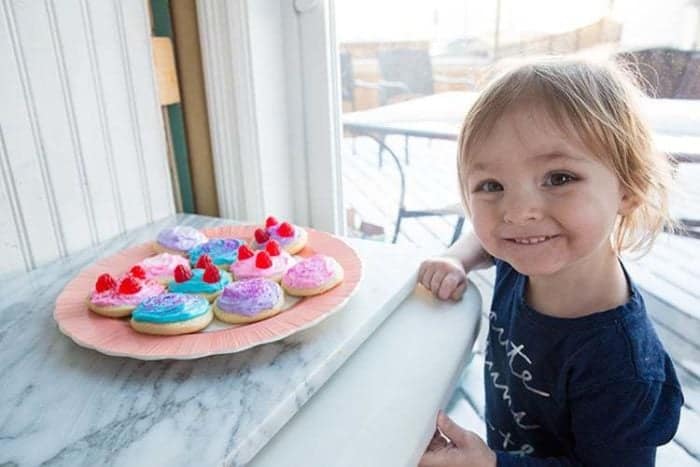 a plate of colorful Old Fashioned Cut-Out Sour Cream Sugar Cookies in front of little girl