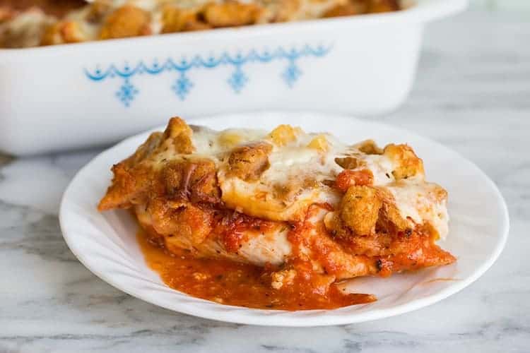 Saucy Chicken Parmesan Casserole in a white plate on a marble background