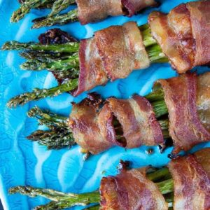 Close up of Bacon Wrapped Asparagus Bundles on a blue plate