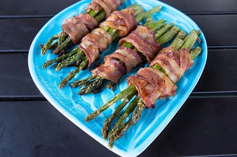4 pieces Bacon Wrapped Asparagus Bundles in a blue plate