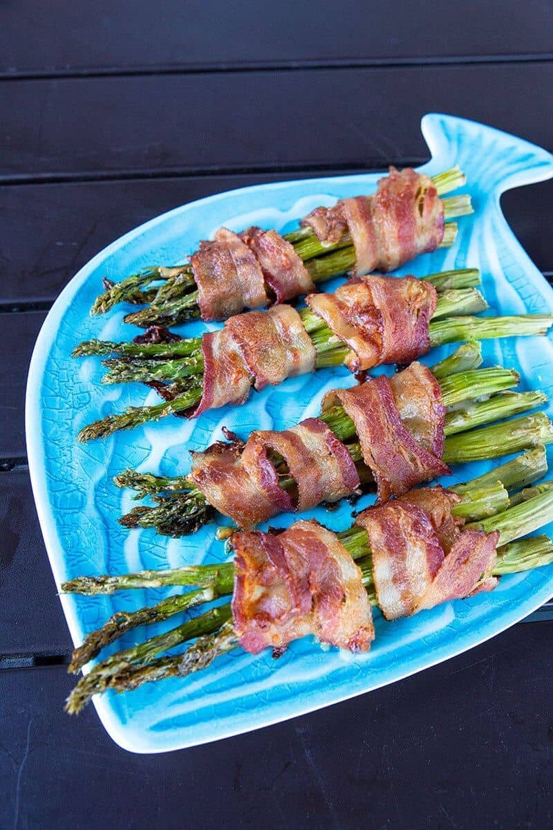  top down shot of Bacon Wrapped Asparagus Bundles on a blue fish plate