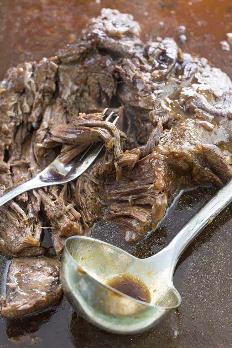 A fork and ladle soup spoon in Instant Pot Roast with gravy