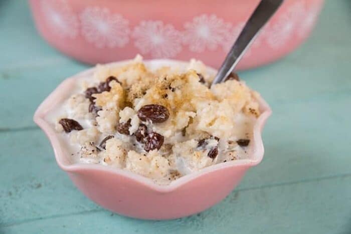 Baked Rice Pudding in a pink bowl sprinkled with cinnamon and nutmeg