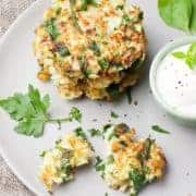 Cabbage and spinach pancakes with yogurt dressing with fresh herbs in a white plate