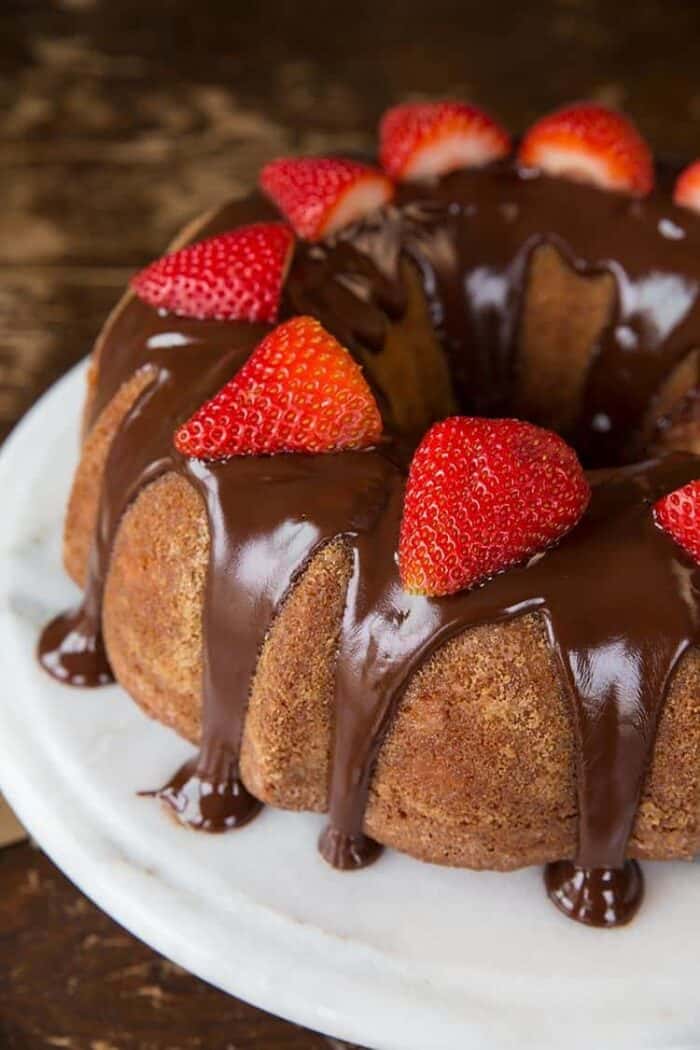 Close up of Strawberry Yogurt Bundt Cake topped with chocolate satin glaze and fresh strawberries