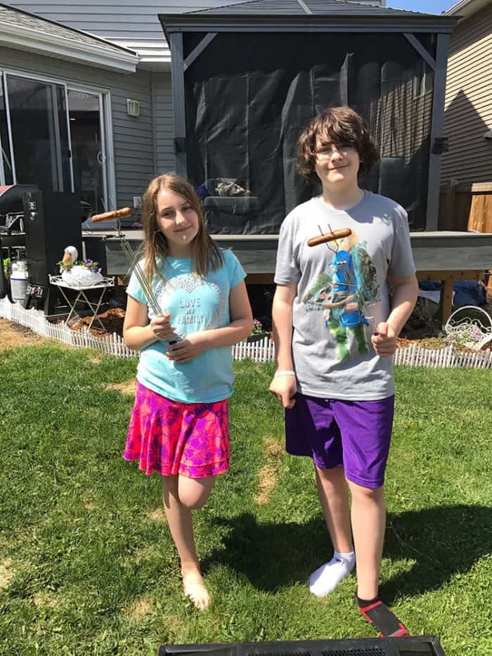 kids holding cooked hot dogs each