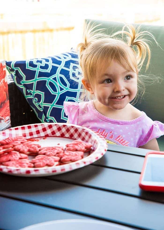 a plate with maple cookies in front of little girl in pink dress 