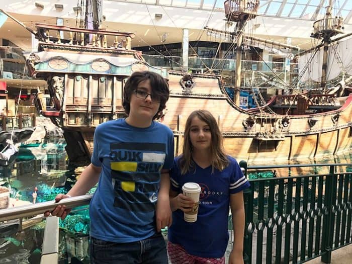 two kids standing near the grills with a large ship in their background