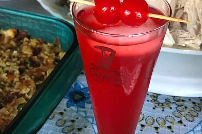 close up of American Fizz Cocktail in a vintage automotive motif glass garnish with cherries in pick