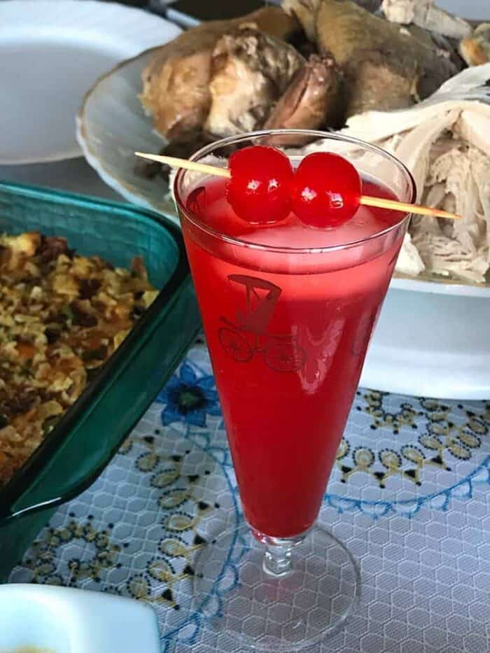 close up of American Fizz Cocktail in a vintage automotive motif glass garnish with cherries in pick