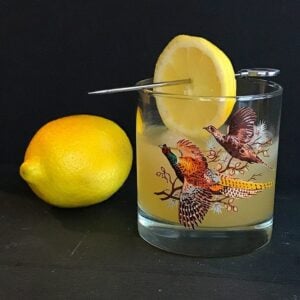 Fresh lemon fruit beside a vintage glass with Boating Punch Cocktail garnish with a slice of lemon