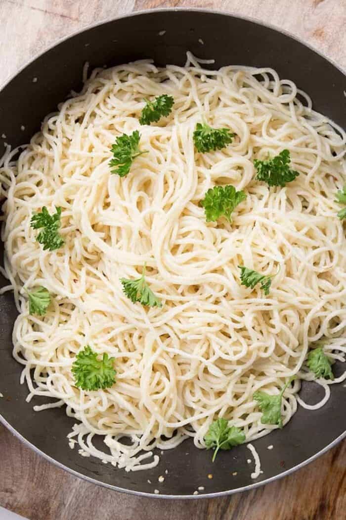 close up of Spaghetti Aglio E Olio in a large skillet with garnished with parsley on top