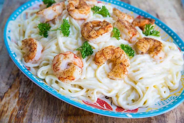 Shrimp Alfredo - sauce covered noodles on a plate with fried shrimps on top