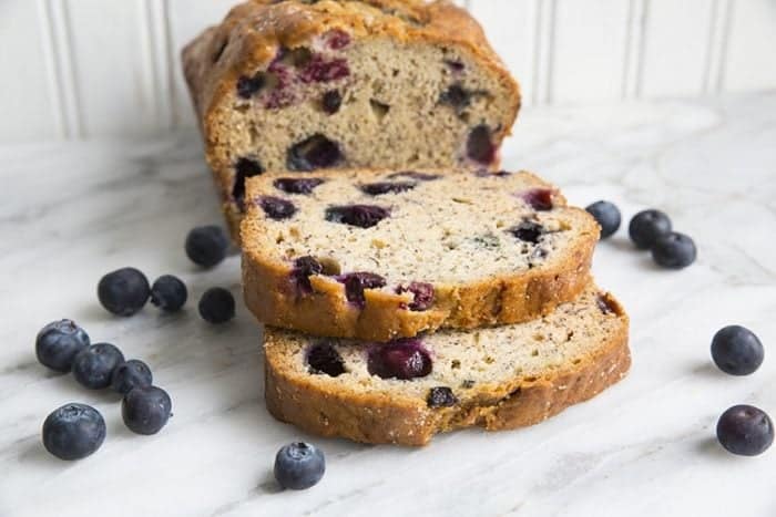 slices of Blueberry Banana Bread and fresh blueberries around