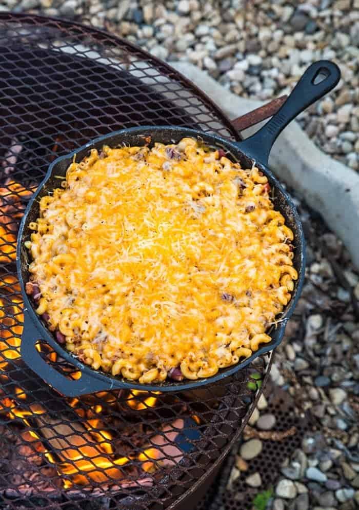 Macaroni, chili and cheese in a skillet over a grill