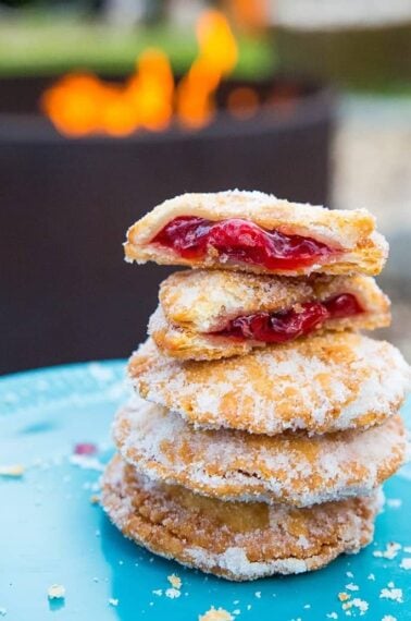 close up of Campfire Cherry Hand Pies in a blue plate with one piece broken into two showing the inside