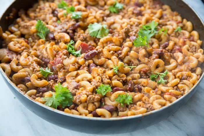 Cheesy Chili Mac Skillet topped with parsley in marble background