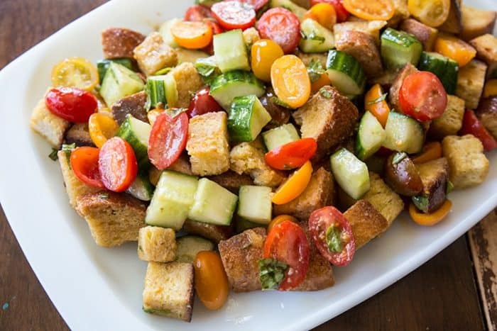 A plate of Panzanella Salad with cherry tomatoes, cucumbers and a basil