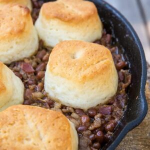 Close up Pork & Beans Cowboy Casserole iron skillet with biscuits on top