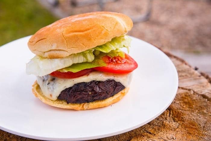 white plate with Portobello Mushroom Burgers with slices of tomatoes and lettuce
