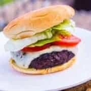 close up of Homemade Portobello Mushroom Burger in white plate with slices of tomatoes and lettuce