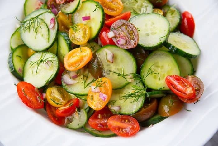 a bowl with Cucumber Salad topped with Tomato and Dill