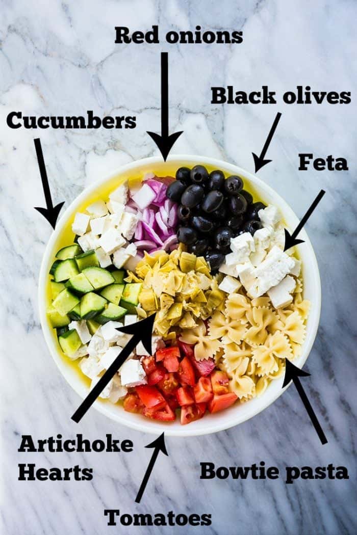 top down shot of Ingredients for Greek Pasta Salad on a marble background