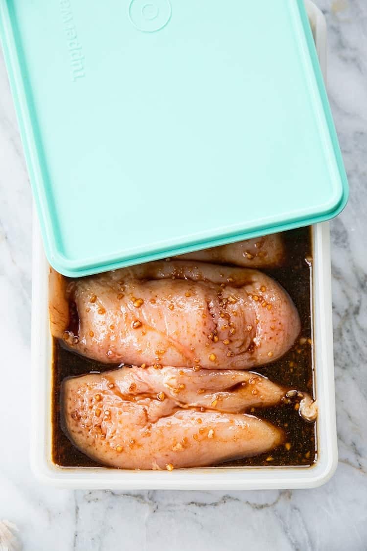 chicken burgers in a rectangular container marinading for the burgers