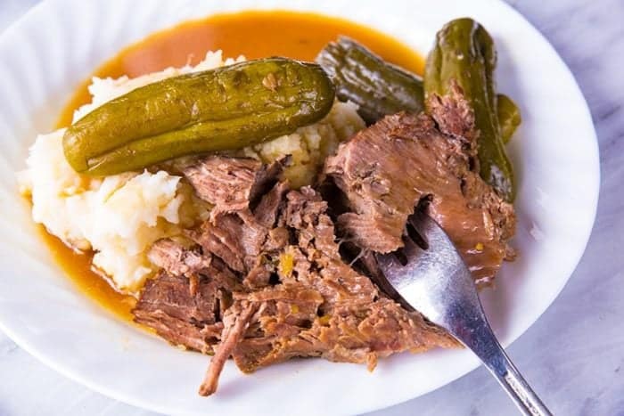 Pot Roast with pickles and gravy in white plate