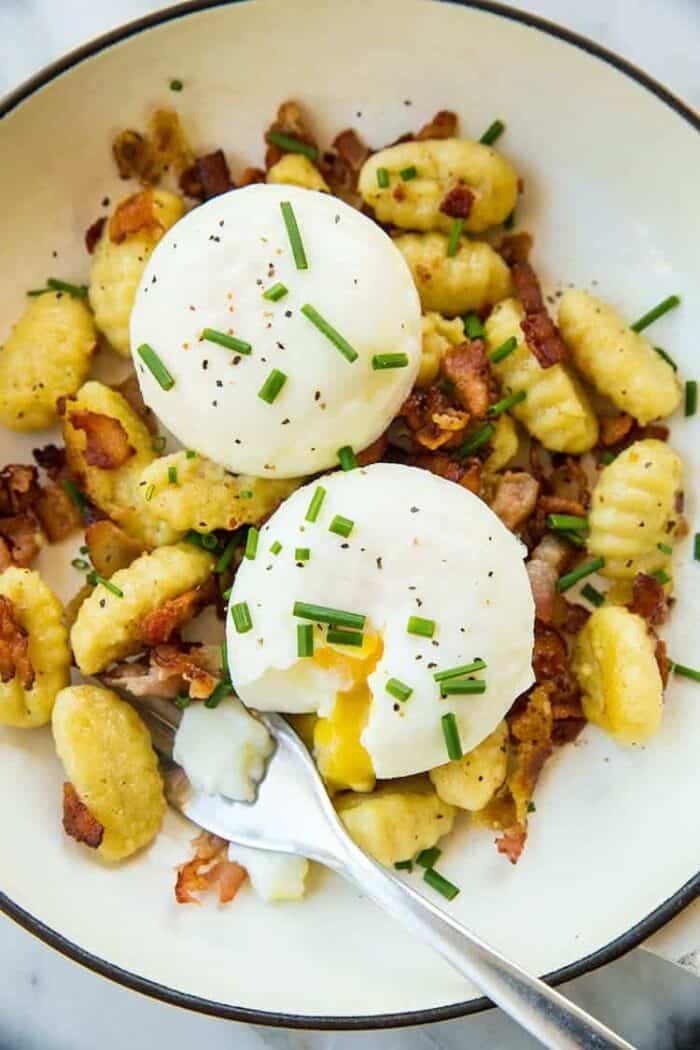 top down shot of Gnocchi Breakfast Skillet with bacon, green onions and top with eggs
