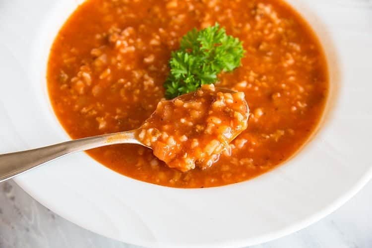 white plate with Tomato & Rice Hamburger Soup and a spoon in it