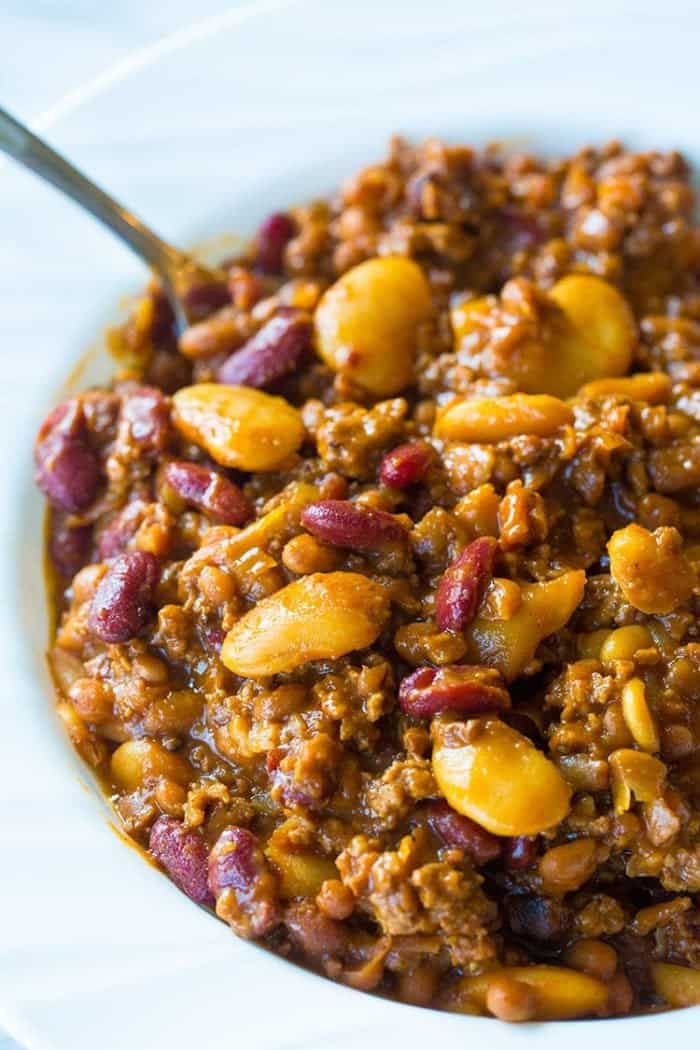 close up of calico beans in a white plate bowl with spoon