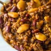 close up of Slow Cooker Calico Beans in a white bowl with spoon