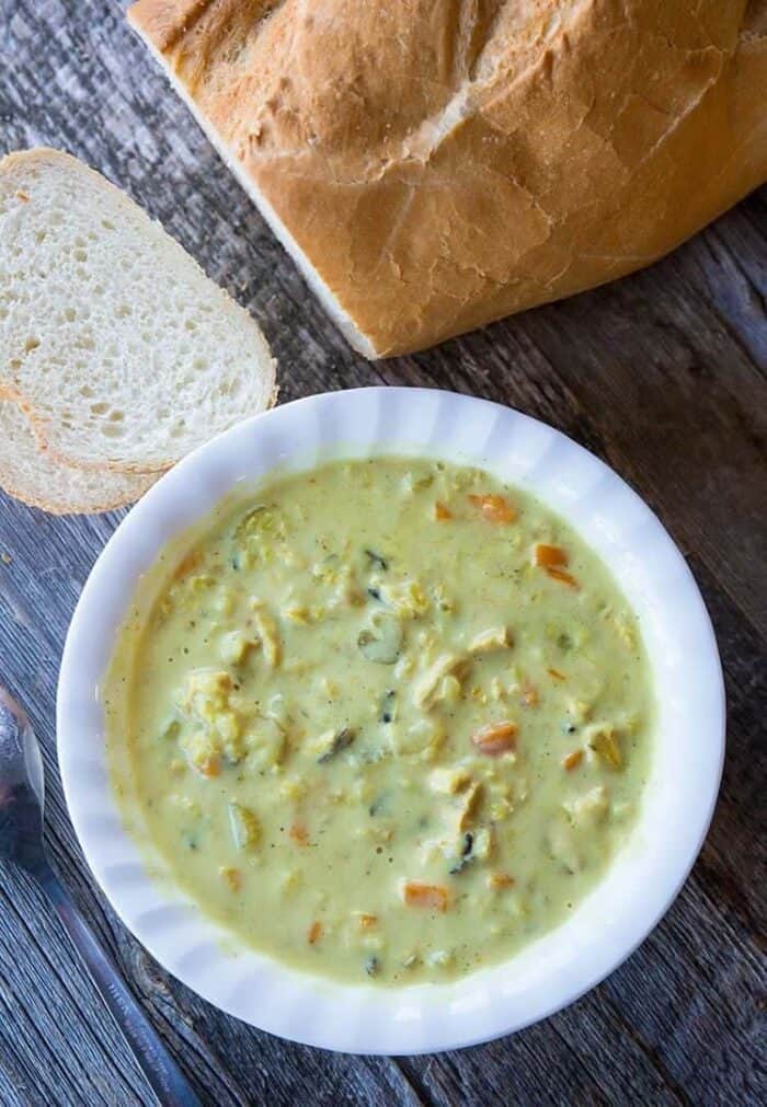 white soup bowl with Crock pot Chicken & Wild Rice Soup and loaf of French bread on side