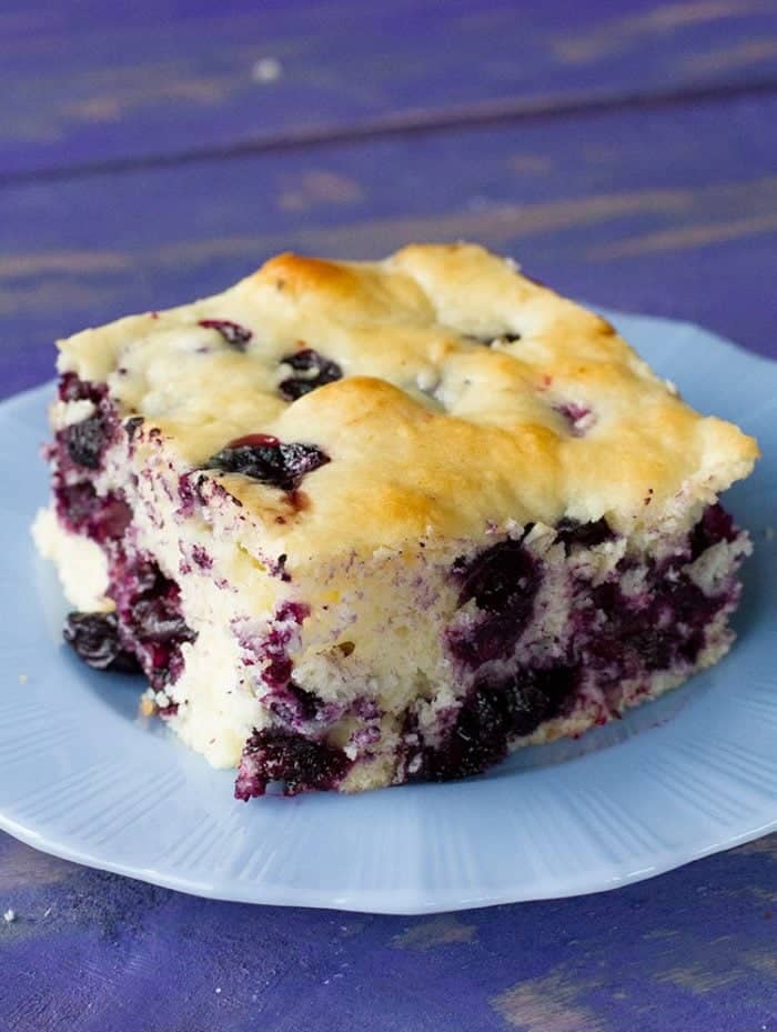 a slice of Breakfast Cake in a blue dessert plate with a bliss of lemon and blueberry