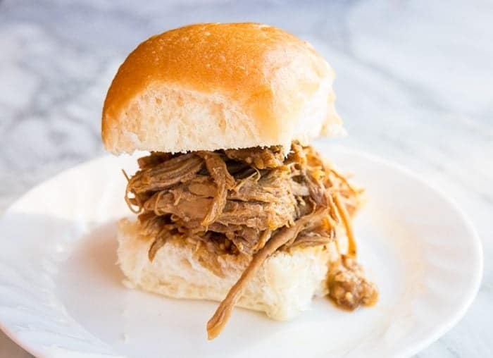 Slow Cooker Texas Pulled Pork Sandwich in a white plate on a marble background