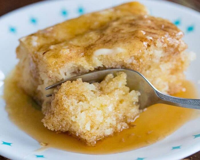 a slice of Baked Cinnamon Pancake Cake in a white plate with syrup