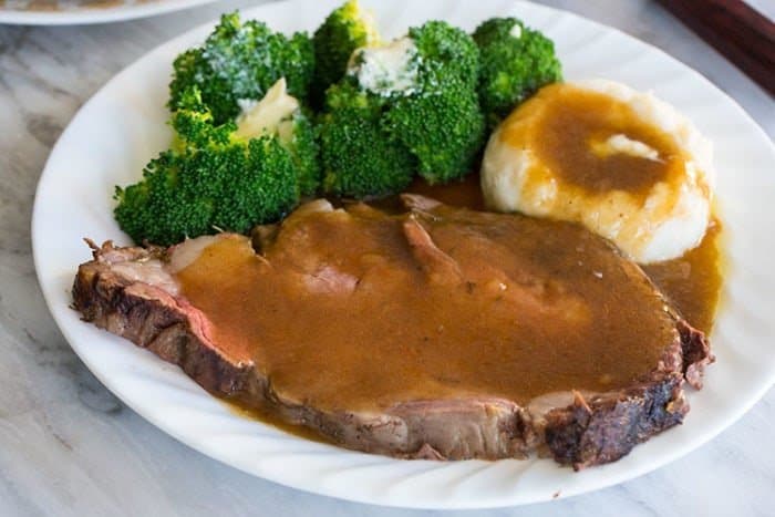 Herb & Garlic Stuffed Prime Rib Roast in a white plate with broccoli and mashed potato