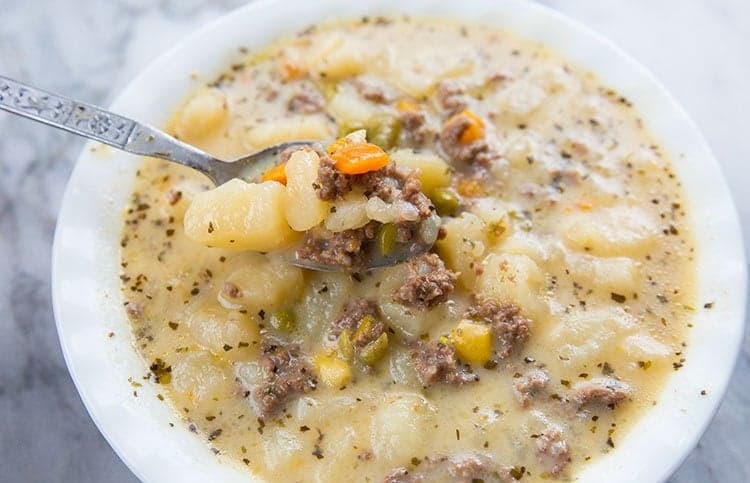 cream based hamburger soup in a white soup bowl with a spoon