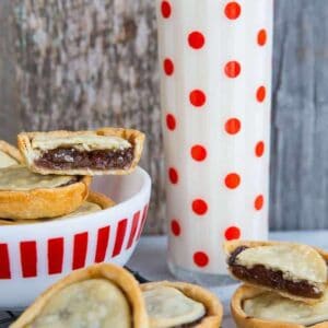 close up bowl of mincemeat tarts and a tall glass of milk