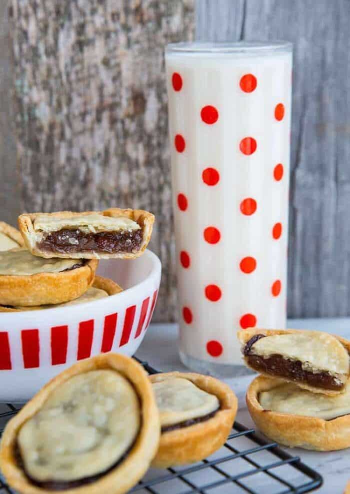 close up bowl of mincemeat tarts and a tall glass of milk